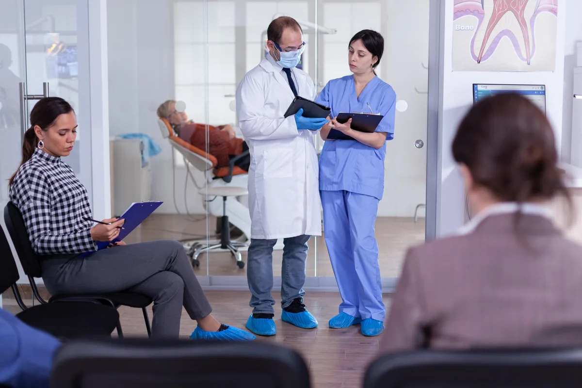 Limpieza Dental en Tamarac: Qué Incluye la Primera Visita y Cada Cuánto Volver 3 Un odontólogo y una asistente revisan la historia clínica de un paciente en el consultorio