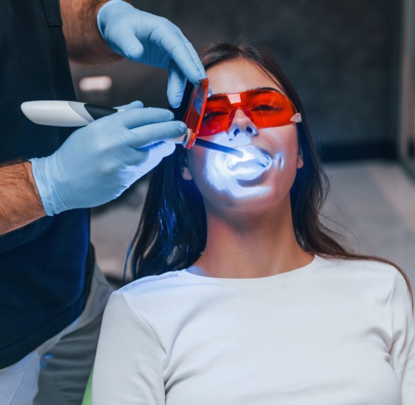 Beautiful woman in red protective glasses have a visit in the dentist clinic. Conception of stomatology.