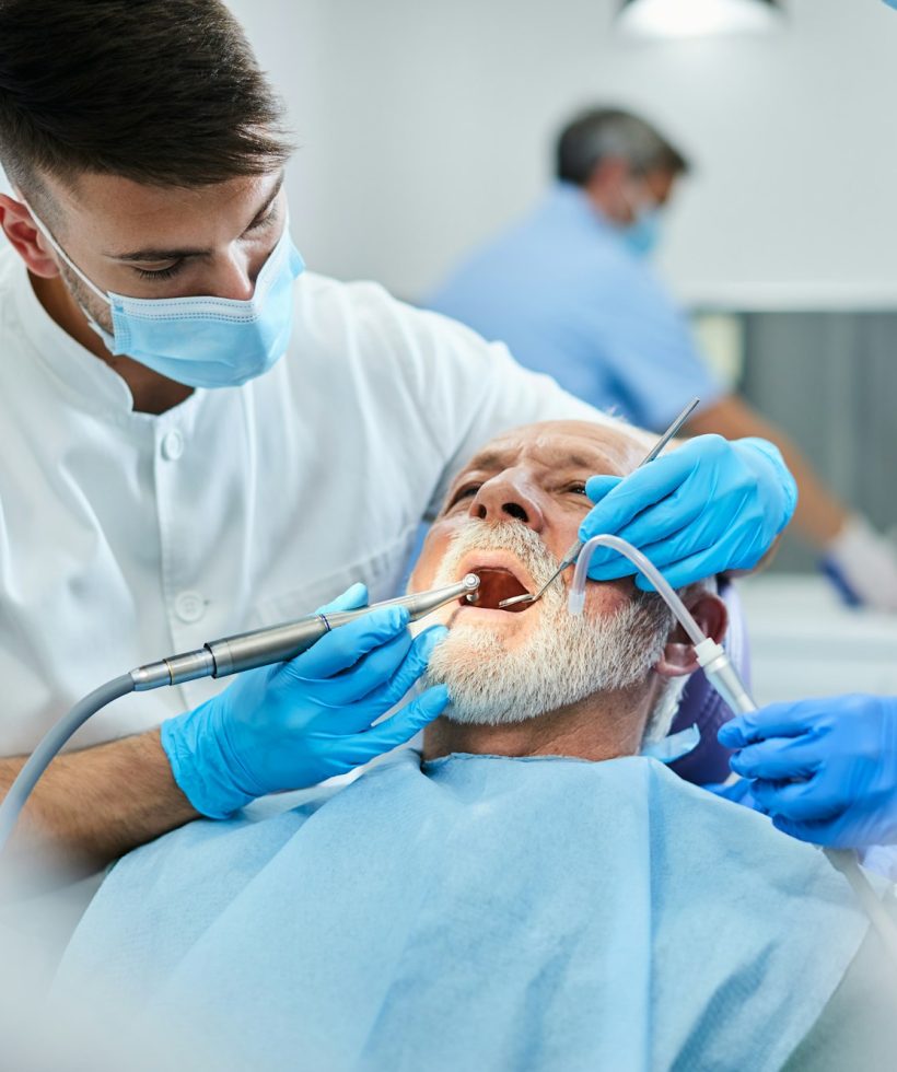 Senior man having teeth polish procedure during appointment with dentist at clinic.